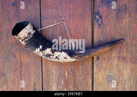 Ancien cor de poudre accroché à un mur de planches délavé avec une corde Banque D'Images