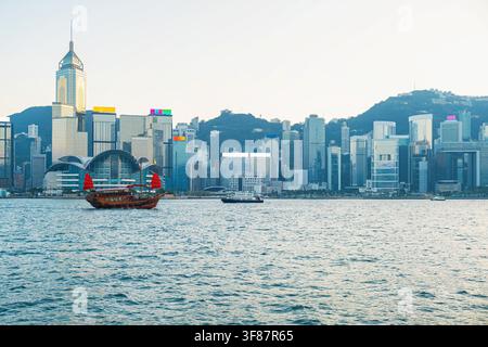 Bateau à voile traditionnel sur le Victoria Harbour face à la skyline moderne de la ville de Hong Kong, Chine. Architecture contemporaine, tourisme, héritage culturel Banque D'Images