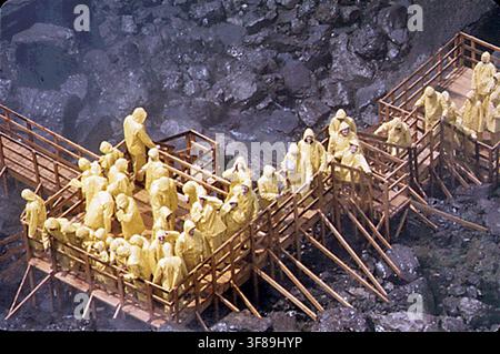 La rampe d'observation de la "Grotte des Vents" à la base des chutes du Niagara américaines, où les touristes, vêtus de vêtements de pluie jaunes, admirent les chutes Bridal Veil, photographiées en 1973 dans le cadre du programme DOCUMERICA de l'Environmental Protection Agency. Banque D'Images