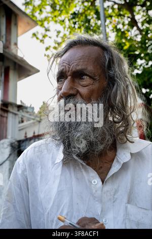Chennai, Inde – 2 août 2026 : Vieil homme indien à la longue barbe grise regardant vers le bas tout en tenant un stylo Banque D'Images