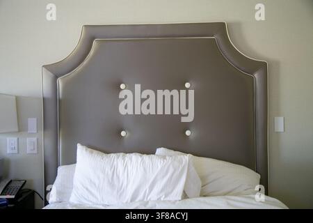 Tête de lit capitonnée grise de style hôtel avec une silhouette courbée gracieuse, des boutons capitonnés blancs décoratifs et une passepoil clair contrasté Banque D'Images