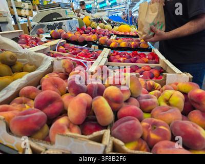 Pfirsics Saturn frais et fruits à noyau d'été exposés sur un étal de marché vibrant Banque D'Images