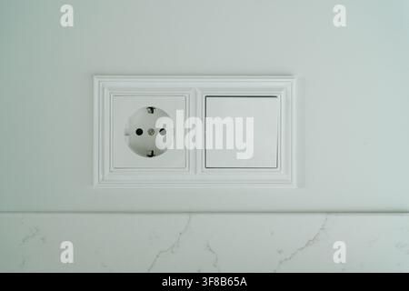 Proche plan net d'une plaque murale double présentant une prise européenne et un bouton d'interrupteur. Photo d'archive parfaite pour les services d'électricien, à la maison Banque D'Images