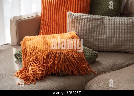 Des textiles d'intérieur doux et texturés comprenant des coussins en velours côtelé et en tricot dans des tons chauds de terre et des couleurs automnales, exposés sur un canapé confortable Banque D'Images