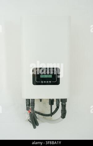 Unité de chauffage électronique compacte installée sur un mur blanc uni dans une buanderie. Image d’archive parfaite pour la technologie de la maison intelligente, l’efficacité énergétique Banque D'Images