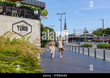 Un couple marchant dans la rue près du marché Balti Jaama à Tallinn, en Estonie, avec la vieille ville en arrière-plan Banque D'Images