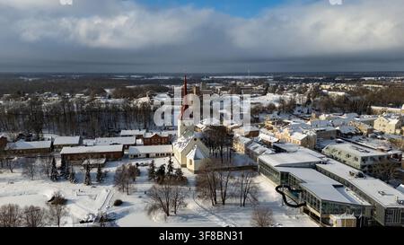 Vue aérienne de l'église de Rakvere et du château historique de Rakvere en arrière-plan, entourée de toits et d'arbres enneigés en hiver à Rakvere, L Banque D'Images