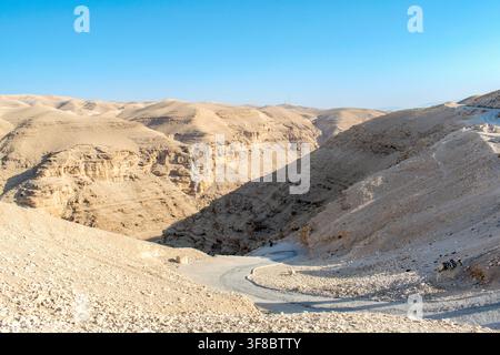 Paysage de canyon du désert de Judée avec une route sinueuse et un âne au loin Banque D'Images