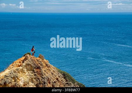 Femme au bord d'une falaise contemplant la vue sur l'Atlantique le long de la côte de Benagil dans l'Algarve, au Portugal Banque D'Images
