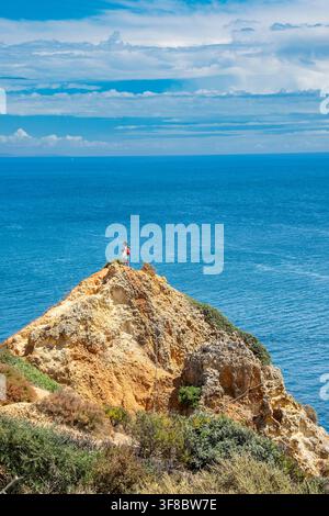 Femme au bord d'une falaise contemplant la vue sur l'Atlantique le long de la côte de Benagil dans l'Algarve, au Portugal Banque D'Images