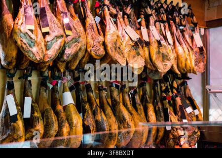 Rangée de jamon de jambes pendantes avec des étiquettes sur la vitrine de la boucherie Banque D'Images