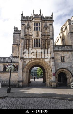 Vue de la porte historique de l'abbaye de la cathédrale de Bristol avec ses sculptures ornées en pierre, son entrée en arc et une personne traversant la porte dans Banque D'Images
