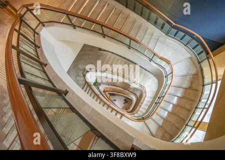 Vue de l'escalier en colimaçon du Peninsula Tokyo avec des marches en marbre élégantes et des rampes en verre à Chiyoda City, Tokyo, Japon. Banque D'Images