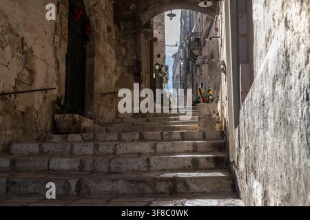 Vue d'un escalier en pierre étroit menant à travers une arche ancienne dans le quartier historique des Sassi de Matera, Basilicate, Italie Banque D'Images