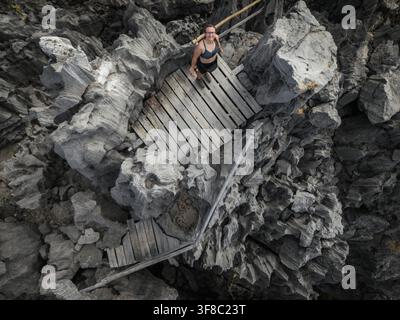 Vue aérienne d'une femme debout sur une plateforme en bois entourée de formations rocheuses tsingy en calcaire aigu dans la réserve spéciale d'Ankarana, Diana, M Banque D'Images