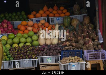 Variété de fruits frais, courges et légumes racines exposés dans des caisses au marché de Kopeng, Java central, Indonésie. Banque D'Images