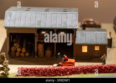 Une vue rapprochée montre un bâtiment d'entrepôt miniature détaillé avec du bois empilé, un petit chariot élévateur et des figurines d'ouvriers dans une scène de diorama. Banque D'Images