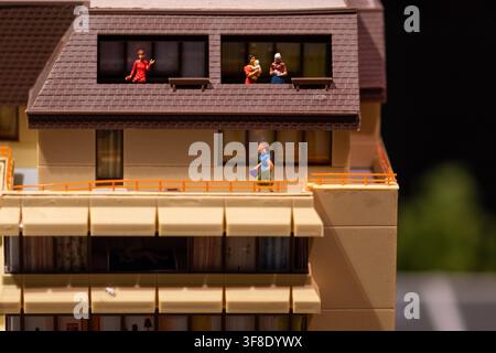Une vue rapprochée montre un modèle réduit d'immeuble d'appartements avec de petites figurines humaines dans les fenêtres et sur une passerelle extérieure. Banque D'Images
