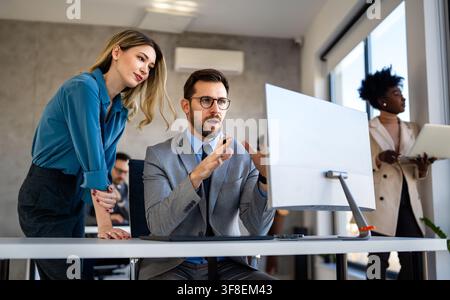 Hommes d'affaires avec des négociants collègues au bureau surveillant les données des stocks sur l'écran analysant le flux de prix Banque D'Images