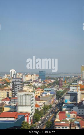 Monument du pavillon doré avec statue debout dans la place de Phnom Penh sous un ciel bleu clair et l'horizon urbain, arbres tropicaux et détails ornés du toit Banque D'Images