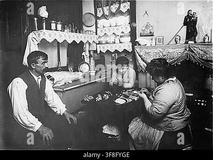 Une famille à New York City faisant des fleurs en soie, avec le père portant un plâtre et un garçon de 11 ans assistant, par Lewis Hine le 29 janvier 1912. Banque D'Images