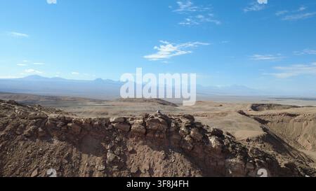 Vue aérienne par drone d'une falaise rocheuse surplombant la vaste plaine du désert d'Atacama près de San Pedro de Atacama, au Chili. Les Andes au loin. Banque D'Images