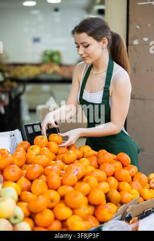 vendeur se tient près d'un comptoir avec des oranges Banque D'Images