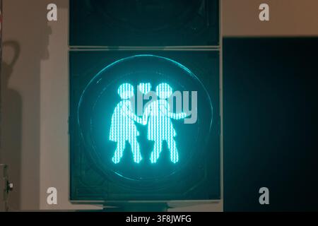 Une vue rapprochée montre un feu piéton vert illuminé d'un symbole familial stylisé. Banque D'Images