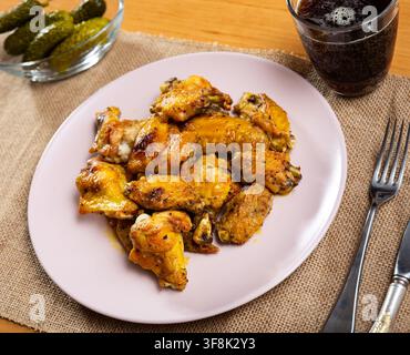 Il y a une collation copieuse sur l'assiette - une grande portion d'ailes de poulet frites avec des concombres marinés. Banque D'Images