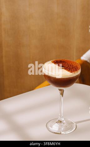 Cocktail Espresso Martini avec grain de café et saupoudrage élégant de poudre de cacao sur une table blanche Banque D'Images