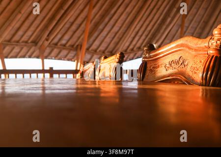 Grossissement d'une chaise en bois sculpté et d'une table dans un pavillon en bambou pendant l'heure dorée au coucher du soleil Banque D'Images