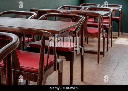 Chaises de restaurant en bois avec coussins rouges et tables disposées dans un café vide. Banque D'Images
