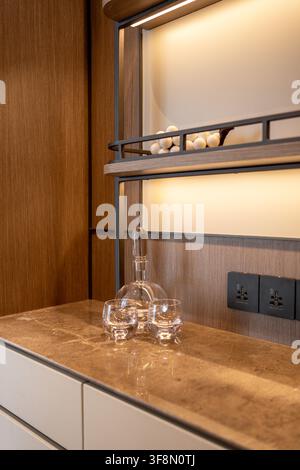 Carafe en verre et deux verres assortis sur un comptoir de minibar en marbre moderne. Banque D'Images