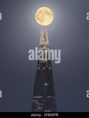 Londres, Royaume-Uni – 18 septembre 2024 : Vue du Shard illuminé la nuit avec une pleine lune positionnée directement au-dessus de sa flèche. Banque D'Images