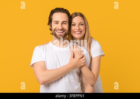 Homme et femme caucasiens heureux souriant ensemble devant un fond jaune Banque D'Images