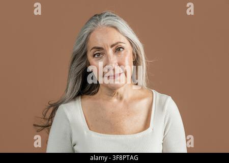 Femme âgée confiante souriant à la caméra avec des cheveux gris, cadre domestique, concept de soins de santé Banque D'Images