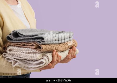 Person tenant une pile de pulls et cardigans tricotés chauds soigneusement pliés, linge et organisation Banque D'Images