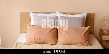 Lit confortable avec tête de lit en bois et divers oreillers dans un design d'intérieur minimaliste de chambre à coucher Banque D'Images