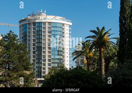 29 juin 2026, Budva, Monténégro : prise fixe d'un immeuble d'appartements moderne en hauteur dans un cadre urbain, avec des palmiers et une végétation luxuriante Banque D'Images