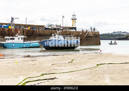 St Ives en Cornouailles, montrant deux bateaux reposant sur le sable près du bord de l'eau. Le bateau bleu foncé nommé Defy est à côté d'un plus petit bateau blanc et bleu Banque D'Images