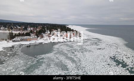 Vue aérienne du phare d'Eagle Harbor entouré de côtes enneigées et des eaux glacées du lac Supérieur à Eagle Harbor, Michigan, États-Unis Banque D'Images