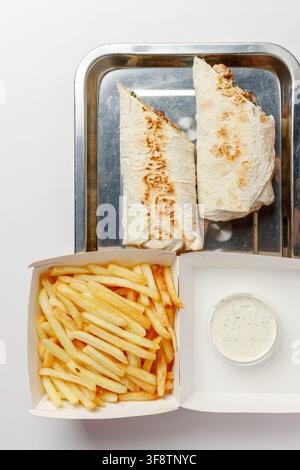 Deux moitiés de shawarma au poulet sur un plateau en métal avec des frites et une sauce à l'ail Banque D'Images