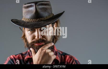 Chapeau de cowboy. Jeune homme séduisant ajustant son chapeau de cowboy. Cowboy mal rasé. Cowboy américain Banque D'Images