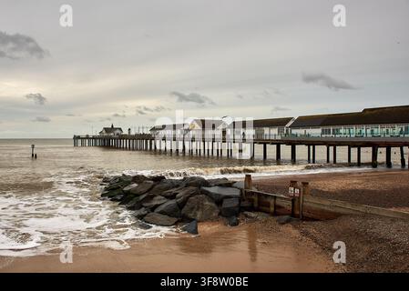Le pier de Southwold s'étendant dans la mer du Nord avec un groyne en pierre et une digue en bois sur la plage sous un ciel nuageux à Southwold, Suffolk. Banque D'Images