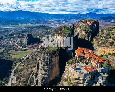 Vue aérienne des monastères du Péloponnèse perchés sur des formations rocheuses imposantes, avec des toits en terre cuite, des routes sinueuses et un vaste paysage montagneux Banque D'Images