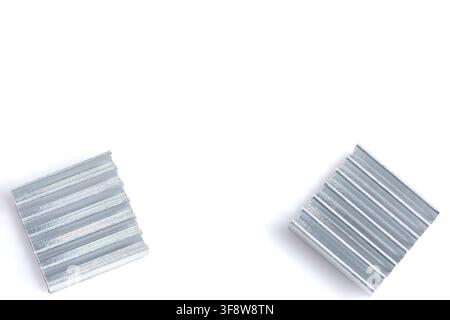 Deux dissipateurs thermiques métalliques reposent sur un fond blanc propre. Leurs surfaces nervurées reflètent un éclairage doux et uniforme. La précision industrielle définit chaque composant Banque D'Images