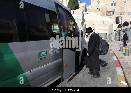 Juif haredi, homme ultra-orthodoxe ou ultraorthodoxe montant dans un bus public, il se trouve à un arrêt de bus près du Mur des Lamentations sous le soleil brûlant de l'été. Banque D'Images