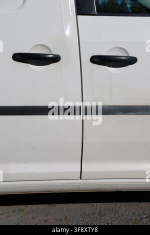 Photo en gros plan d'une poignée de porte extérieure en plastique noir montée sur une porte de véhicule blanche. Banque D'Images