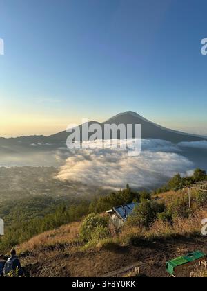 Sommet du volcan Mount Agung s'élevant au-dessus de la mer de nuages au lever du soleil, Mount Batur, Bali, Indonésie Banque D'Images