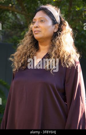 Femme indienne d'âge moyen debout dans le jardin, regardant à droite, portant un chemisier bordeaux et un bandeau Banque D'Images